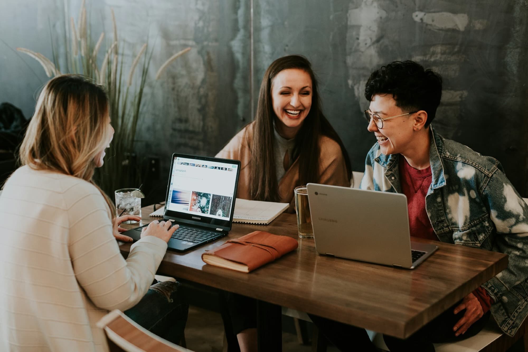 Three colleagues laughing together at a table